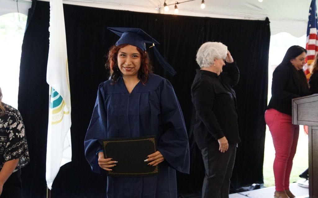 woman in a graduation cap and gown smiling